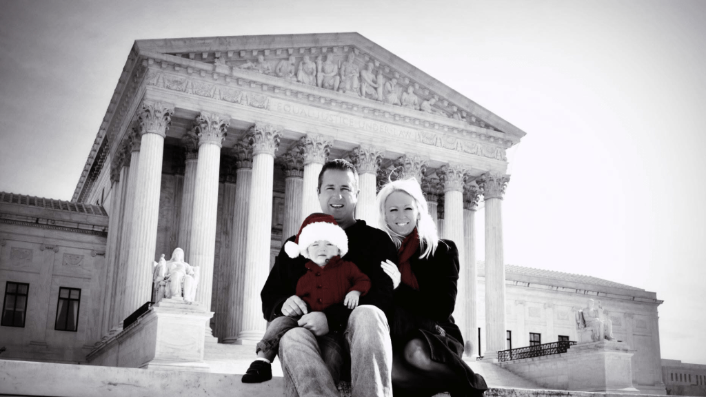 A family posing in front of a prominent building, wearing winter clothing and holiday-themed accessories, with a sense of warmth and togetherness.